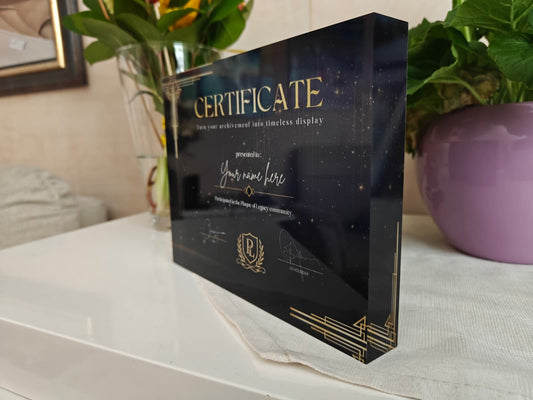 Acrylic certificate holder with gold text on a white surface with plants in the background